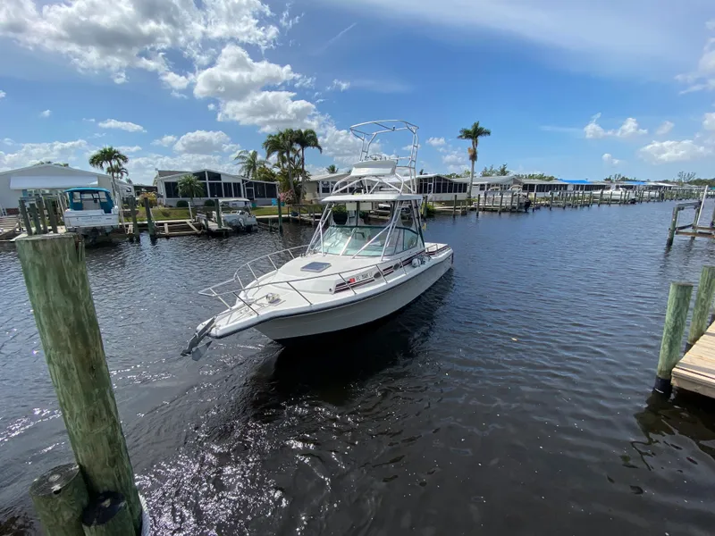 Slide: The Image of 1997 Stamas 310 Express boat cruising in a sunny marina with palm trees. - 43