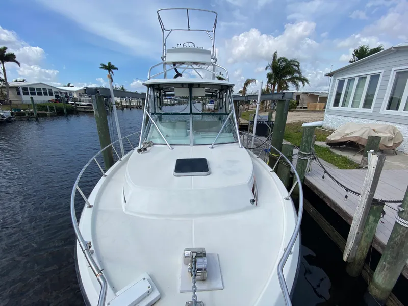 Slide: The Image of 1997 Stamas 310 Express boat docked at a marina with palm trees and houses in the background. - 5