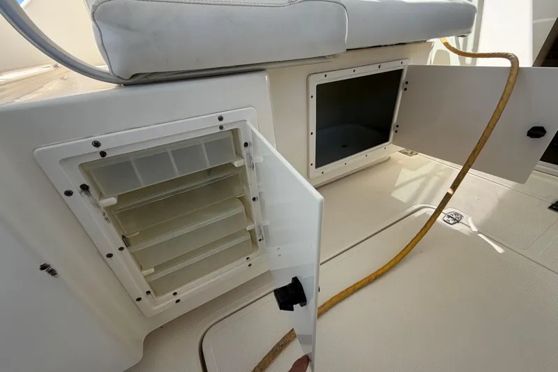 Slide: The Image of 2001 Pursuit 3000 Express boat storage compartments with open doors and visible hose. - 17