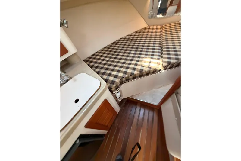 Slide: The Image of 2001 Pursuit 3000 Express cabin interior with plaid bedding and wooden flooring. - 21