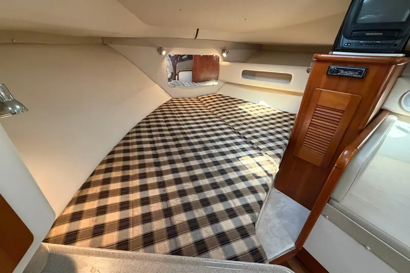 Slide: The Image of 2001 Pursuit 3000 Express cabin with plaid bedding and wooden cabinetry. - 26