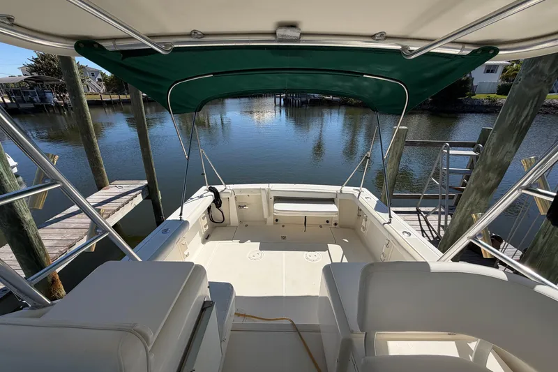 Slide: The Image of 2001 Pursuit 3000 Express boat with green canopy docked by calm waters. - 5