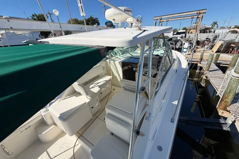 Slide: The Image of 2001 Pursuit 3000 Express boat docked, featuring spacious seating and green canopy. - 8