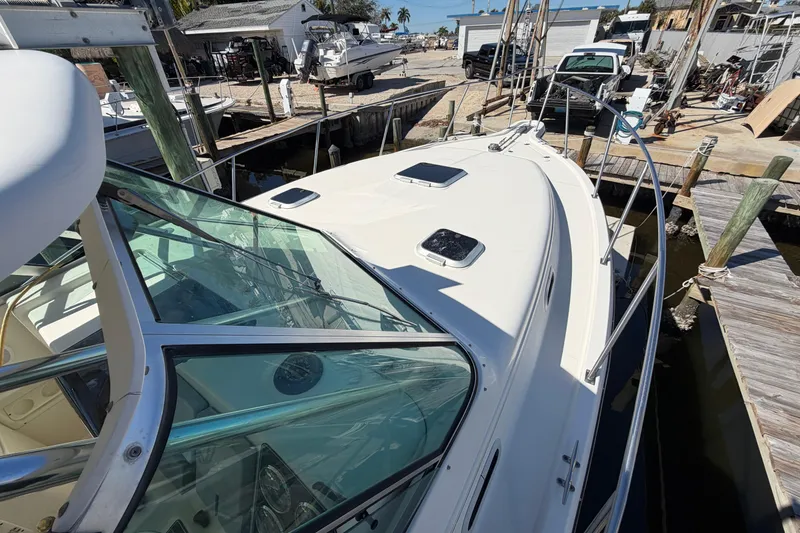 Slide: The Image of 2001 Pursuit 3000 Express boat docked at a marina, showcasing sleek design and glass windows. - 9