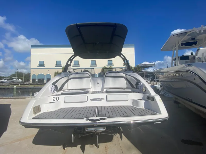 Slide: The Image of 2018 Yamaha Boats 242 Limited S at marina, rear view under sunny sky. - 1