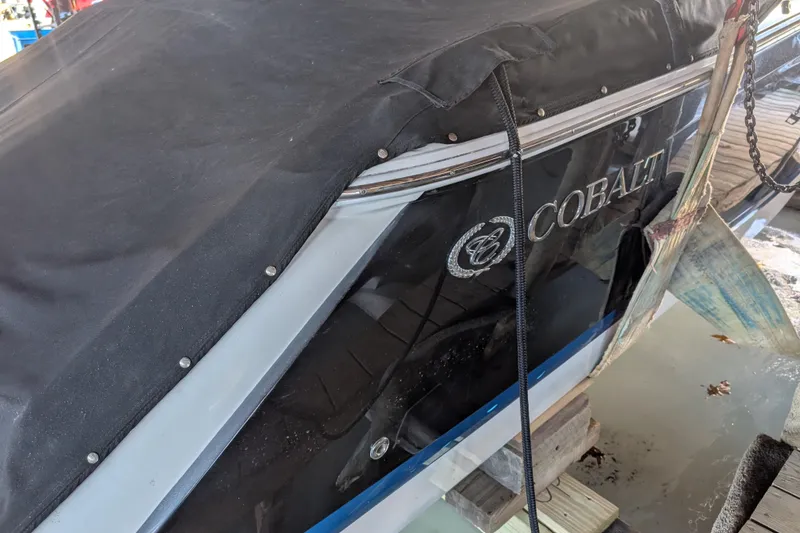 Slide: The Image of 2013 Cobalt 26SD boat with black cover docked on water. - 1