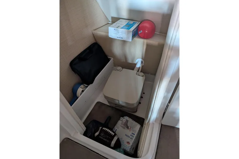 Slide: The Image of Storage compartment in a 2013 Cobalt 26SD boat with various items. - 7
