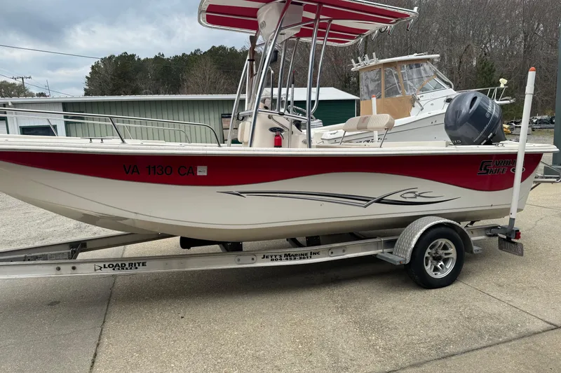 The Image of 2016 Carolina Skiff 218 DLV boat on trailer, red and white design, parked outdoors. - 0