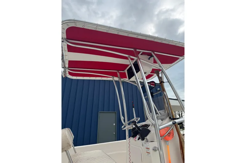 Slide: The Image of 2016 Carolina Skiff 218 DLV boat with red and white canopy, steering console visible. - 6