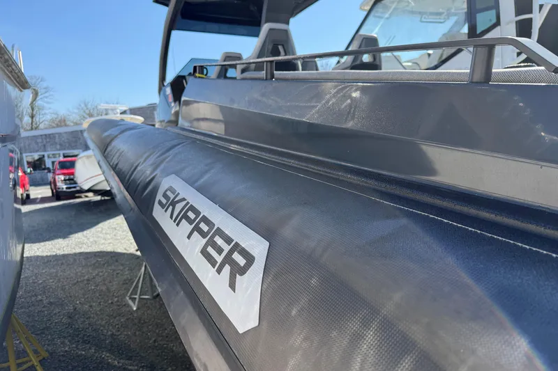 Slide: The Image of 2024 Skipper-BSK 38NC boat side view with logo, parked outdoors. - 18