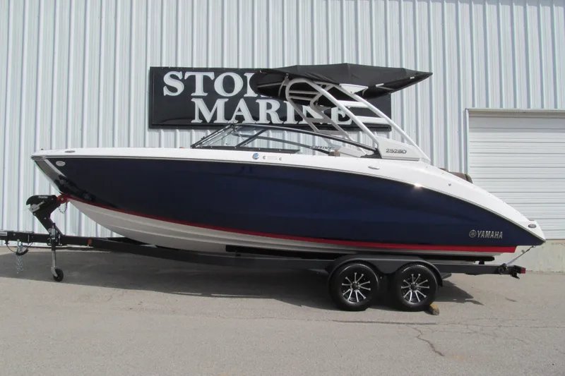 The Image of 2025 Yamaha Boats 252SD in blue, displayed on a trailer outside a marine store. - 1