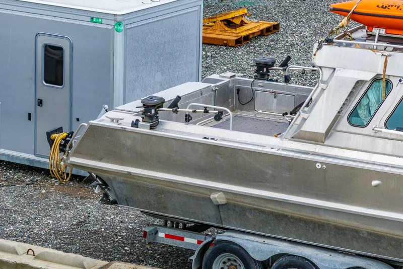 Slide: The Image of 2003 Lifetimer 3050 Pleasure Cabin boat on trailer beside a gray trailer. - 3