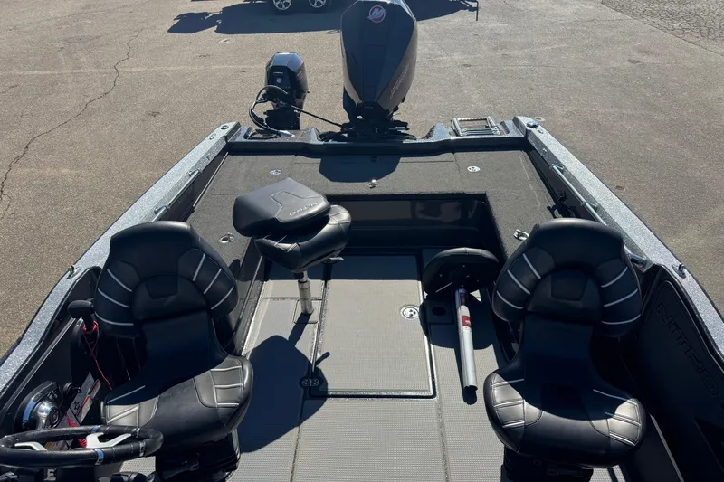 Slide: The Image of 2023 Nitro ZV20 boat interior with black seats and motor, parked on pavement. - 21