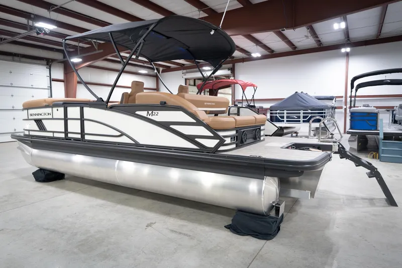 Slide: The Image of 2026 Bennington 22 MSB pontoon boat in a showroom, featuring sleek design and comfortable seating. - 10
