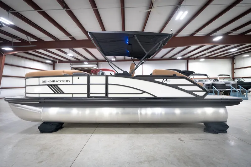 Slide: The Image of 2026 Bennington 22 MSB pontoon boat in a spacious indoor showroom. - 11