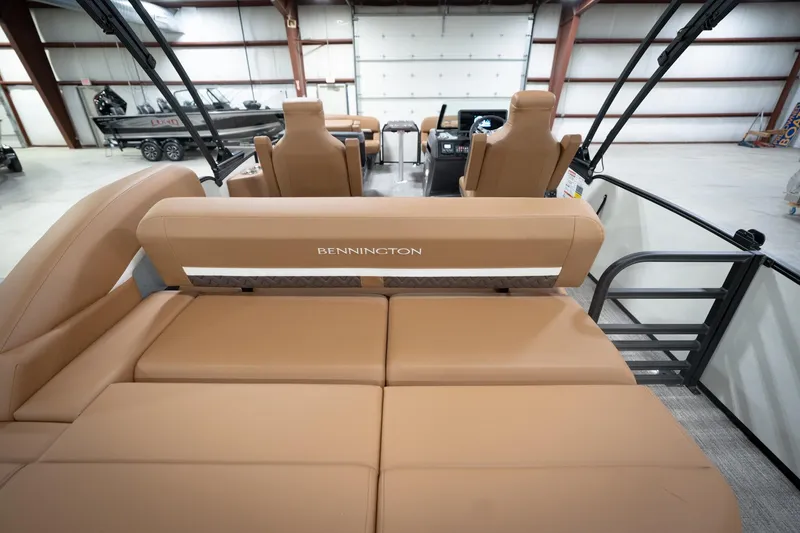 Slide: The Image of 2026 Bennington 22 MSB pontoon boat interior with tan seating in a spacious warehouse. - 19