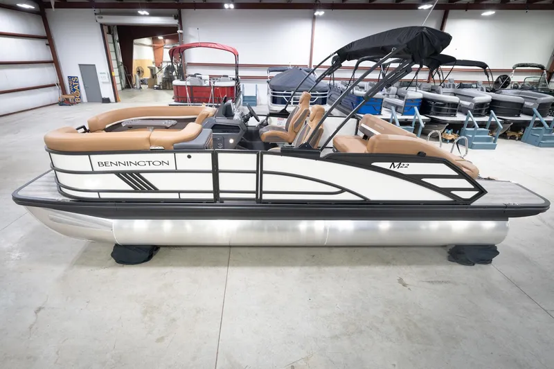 The Image of 2026 Bennington 22 MSB pontoon boat in showroom, featuring sleek design and tan seating. - 2