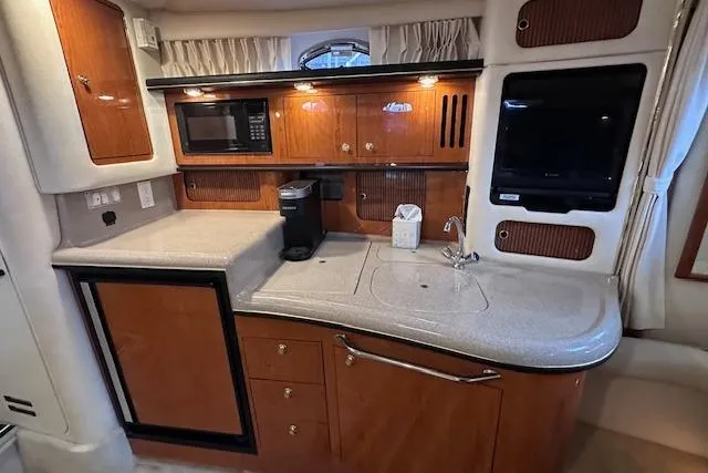 Slide: The Image of 2001 Sea Ray 340 Sundancer yacht kitchen with wood cabinetry, microwave, and sink. - 18