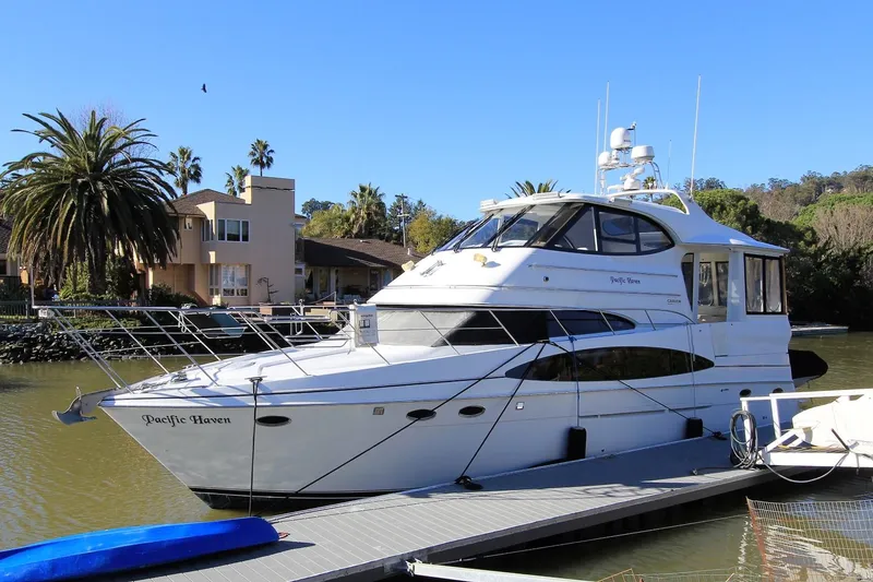 Slide: The Image of 2001 Carver 506 Motor Yacht docked, surrounded by palm trees. - 2