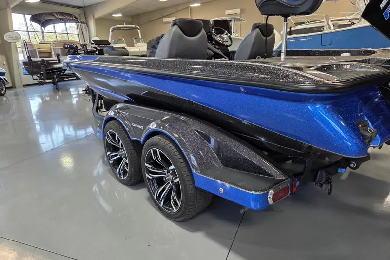 Slide: The Image of 2023 Caymas CX 20 boat in showroom, featuring sleek blue design and dual-axle trailer. - 2