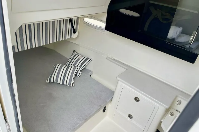 Slide: The Image of 2024 Cobia 350 Center Console cabin interior with striped pillows and storage cabinets. - 5