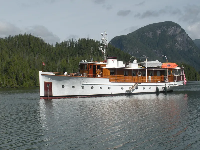 Slide: The Image of 1929 Custom HOFFAR-BEECHING Fantail Yacht on serene water with forested mountains in the background. - 23