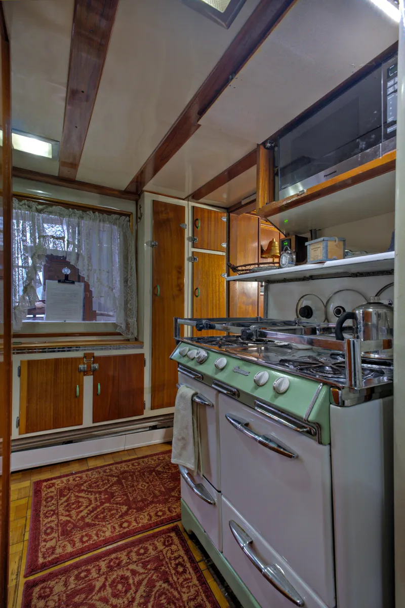 Slide: The Image of 1929 HOFFAR-BEECHING Fantail Yacht kitchen with vintage stove and wooden cabinetry. - 46