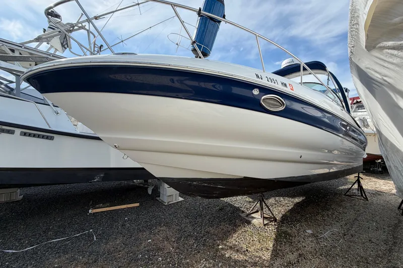 The Image of 2006 Crownline 270 CR boat on stands, blue and white hull, outdoor storage. - 2