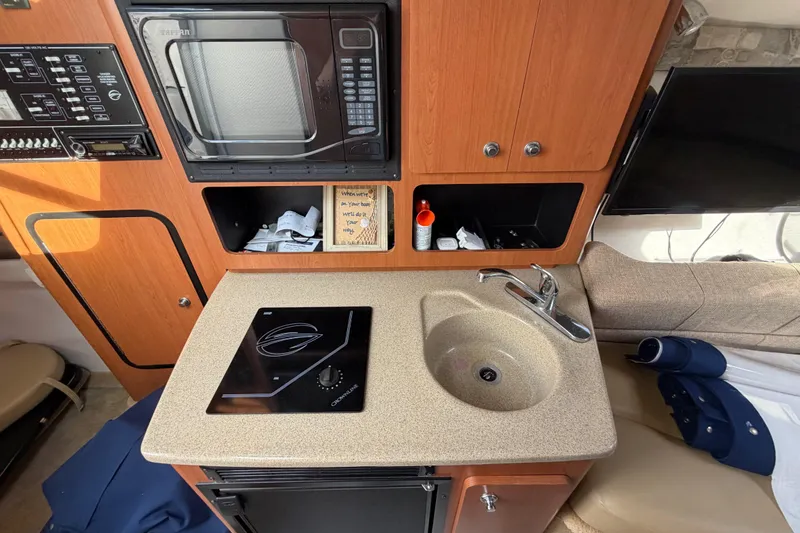 Slide: The Image of 2006 Crownline 270 CR boat interior with kitchenette, microwave, and sink. - 20