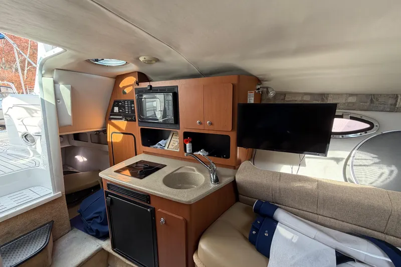Slide: The Image of 2006 Crownline 270 CR cabin interior with kitchenette, TV, and seating area. - 22