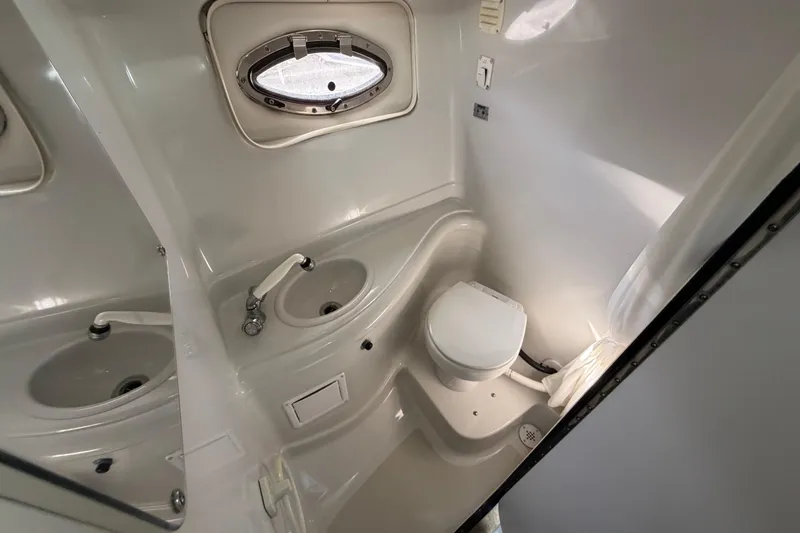 Slide: The Image of 2006 Crownline 270 CR boat bathroom with sink, toilet, and porthole window. - 23