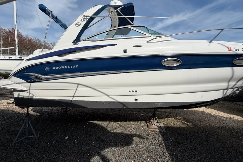 Slide: The Image of 2006 Crownline 270 CR boat on stands, blue and white exterior, sunny day. - 4