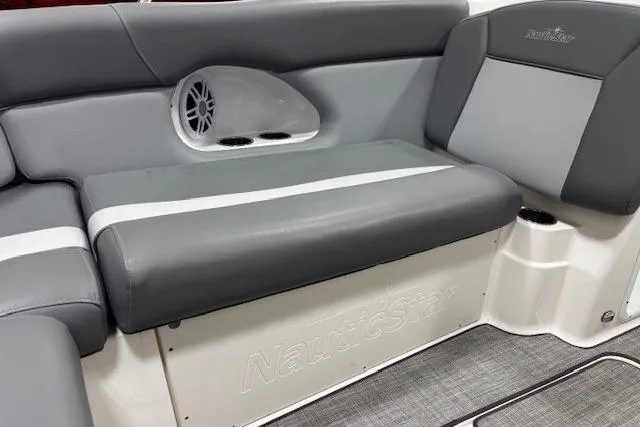 Slide: The Image of 2023 NauticStar 243DC Sport Deck boat in showroom, gray and white exterior. - 12