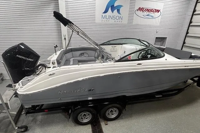 Slide: The Image of 2023 NauticStar 243DC Sport Deck boat on trailer in showroom. - 2