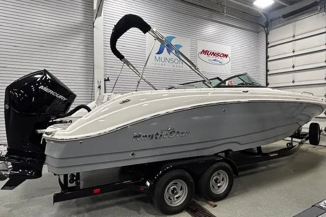 Slide: The Image of 2023 NauticStar 243DC Sport Deck boat with gray and white cushioned seating. - 24