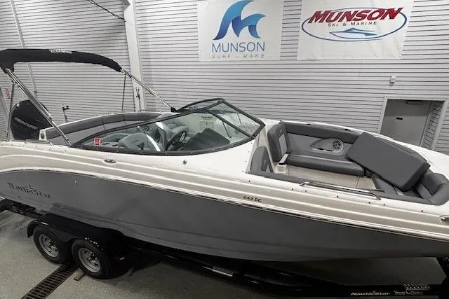 Slide: The Image of 2023 NauticStar 243DC Sport Deck boat in showroom, featuring sleek design and Mercury engine. - 4