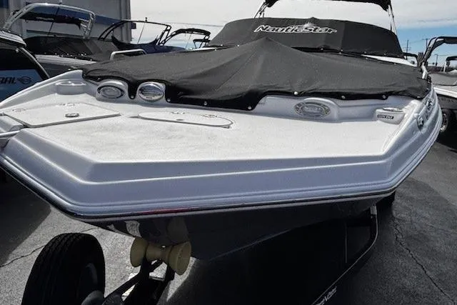 Slide: The Image of 2023 NauticStar 243 DC boat with cover, docked in marina. - 52