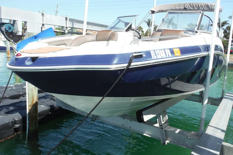 Slide: The Image of 2011 Yamaha Boats 242 Limited on lift, docked in clear water. - 2