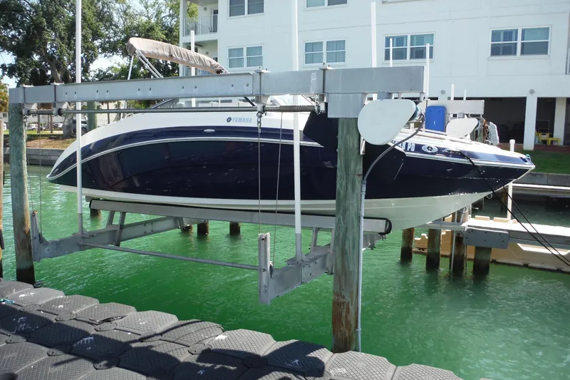 Slide: The Image of 2011 Yamaha Boats 242 Limited on lift, docked near waterfront building. - 41