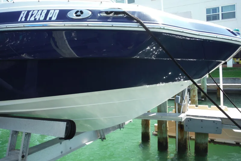 Slide: The Image of 2011 Yamaha Boats 242 Limited on lift, docked in marina with clear water. - 43