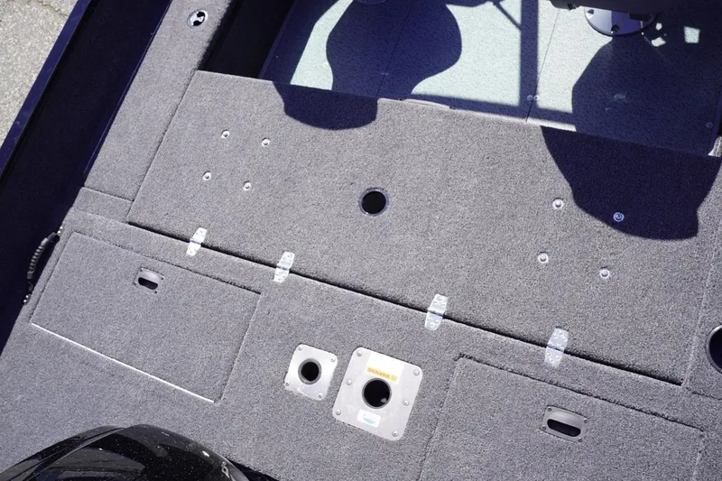 Slide: The Image of 2026 Lowe Fishing Machine 1675 WT boat deck with storage compartments and carpeted surface. - 25