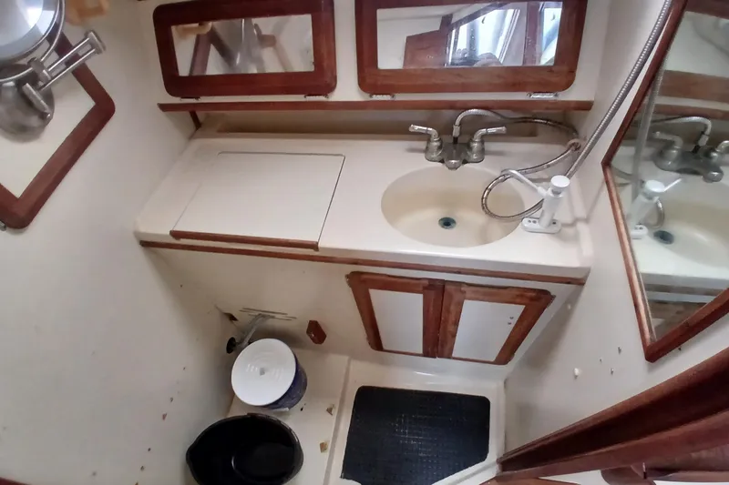 Slide: The Image of Compact bathroom in a 1994 Hunter 30 sailboat with sink, mirror, and storage cabinets. - 11