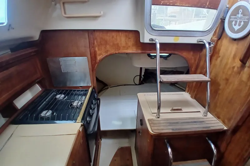 Slide: The Image of Interior of a 1994 Hunter 30 sailboat featuring a compact kitchen and wooden cabinetry. - 6