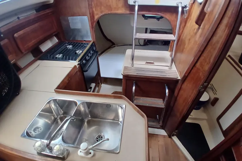 Slide: The Image of Interior of a 1994 Hunter 30 sailboat featuring a compact kitchen and wooden cabinetry. - 8