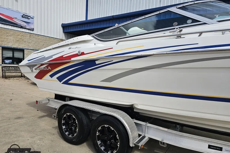 Slide: The Image of 2008 Formula 271 FASTech boat with colorful graphics on a trailer outside a building. - 7