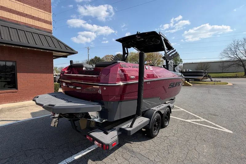 Slide: The Image of 2023 Supra SL 550 boat in parking lot, red and gray design, sunny day. - 3