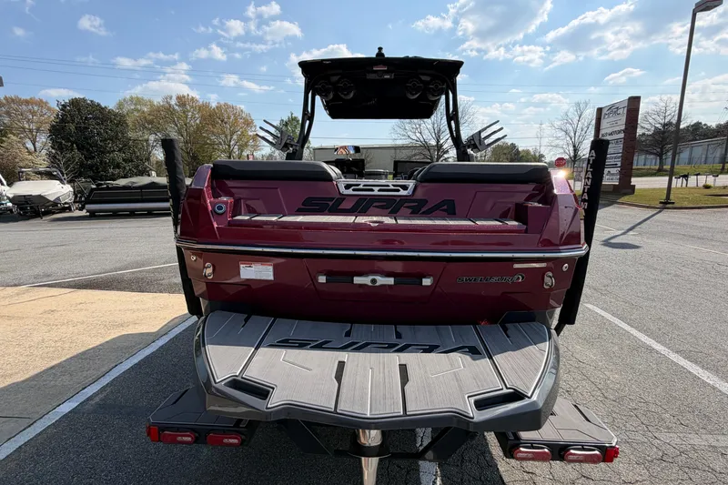 Slide: The Image of 2023 Supra SL 550 boat rear view with SwellSurf technology, parked outdoors. - 5