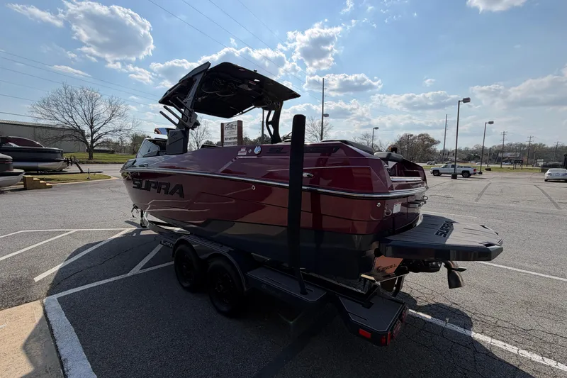Slide: The Image of 2023 Supra SL 550 boat on trailer in parking lot under cloudy sky. - 6