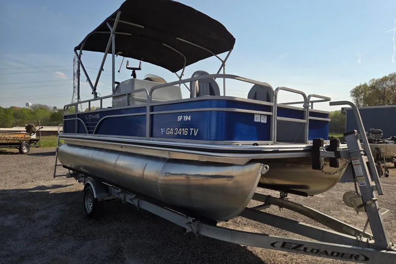 Slide: The Image of 2022 Lowe SF 194 Sport Fish pontoon boat on trailer, blue exterior, sunny day. - 3