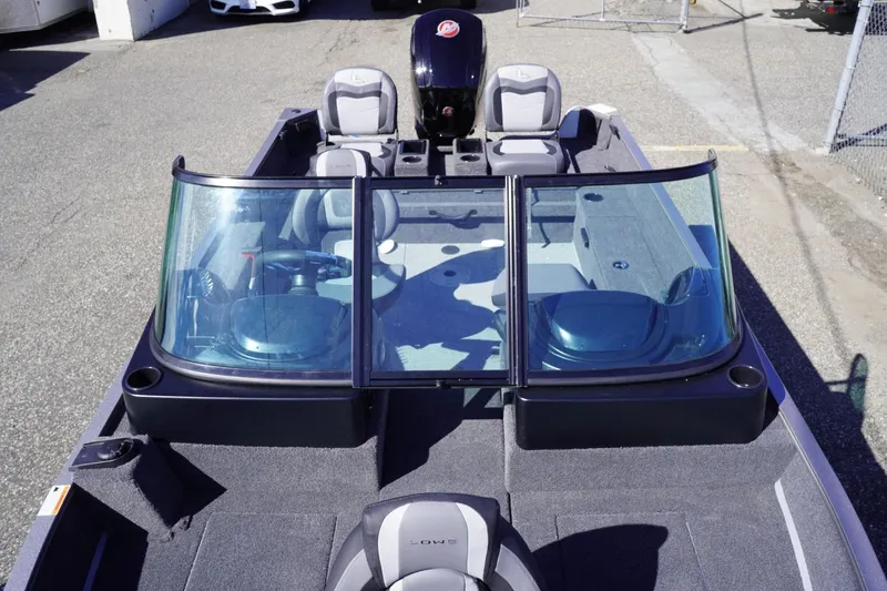 Slide: The Image of 2026 Lowe Fishing Machine 1775WT boat with windshield and seating, parked outdoors. - 11